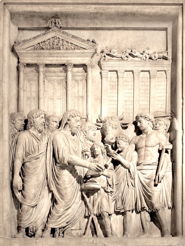 Marcus Aurelius capite velato carries out a sacrifice. By his left side is a flamen wearing an apex. The victima is the bull, who will be struck by the popa to the right. The music of the aulos was to drive off inauspicious noise. The setting is the Temple of Capitoline Jupiter.