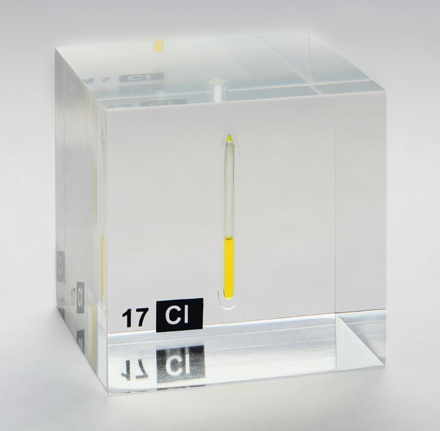 Chlorine, liquefied under a pressure of 7.4 bar at room temperature, displayed in a quartz ampule embedded in acrylic glass.
