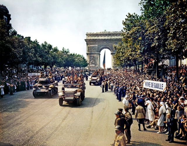 The 2nd Armored Division passes through the Arc de Triomphe. Signs read "Long live de Gaulle" and "De Gaulle to power".
