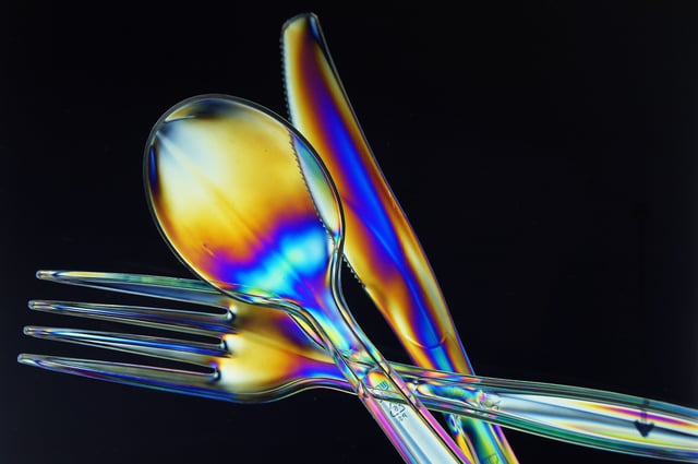 Light polarization shown on clear polystyrene cutlery between crossed polarizers