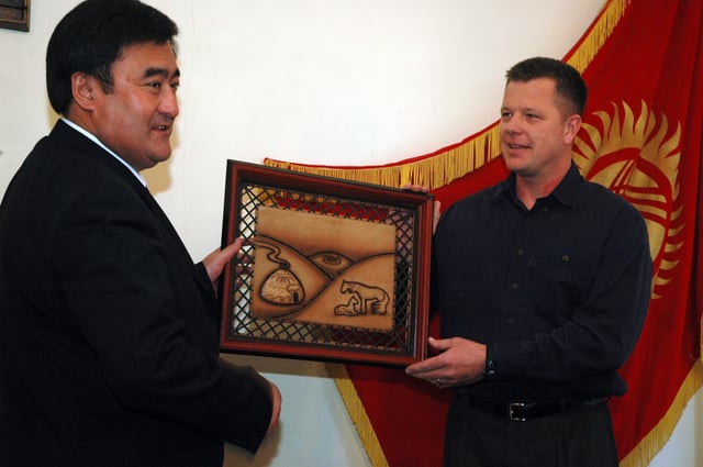 Bishkek mayor Arstanbek Nogoev presents a gift for Colorado Springs mayor Lionel Rivera to a US airman at Manas Air Base, in a ceremony aimed at reviving ties between the two sister cities.