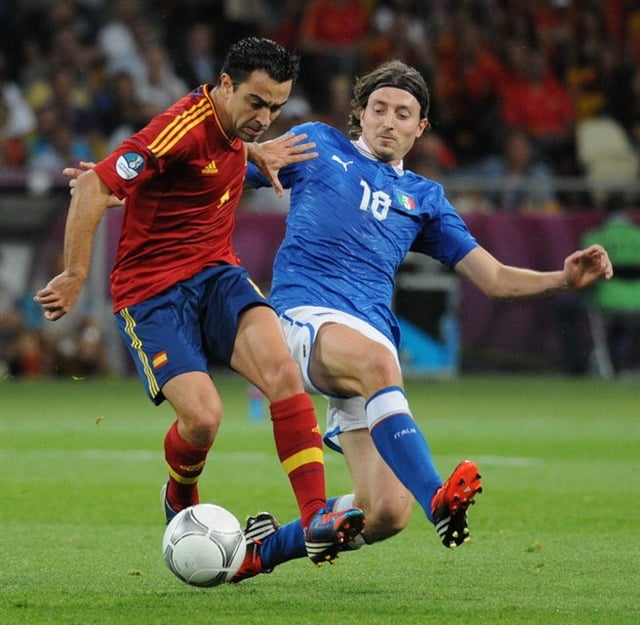 Xavi (left) turns away from Italy's Riccardo Montolivo in the Euro 2012 final