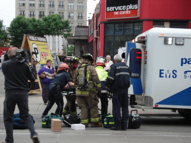 Firefighters assist while paramedics from the Toronto Paramedic Services load a patient into an ambulance.