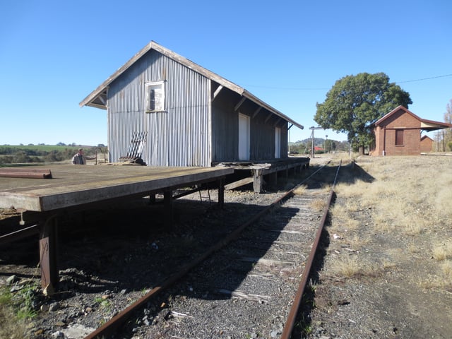 Derelict industrial rail siding showing old platform and warehouse at the disused Galong railway station, Australia (circa 2016)