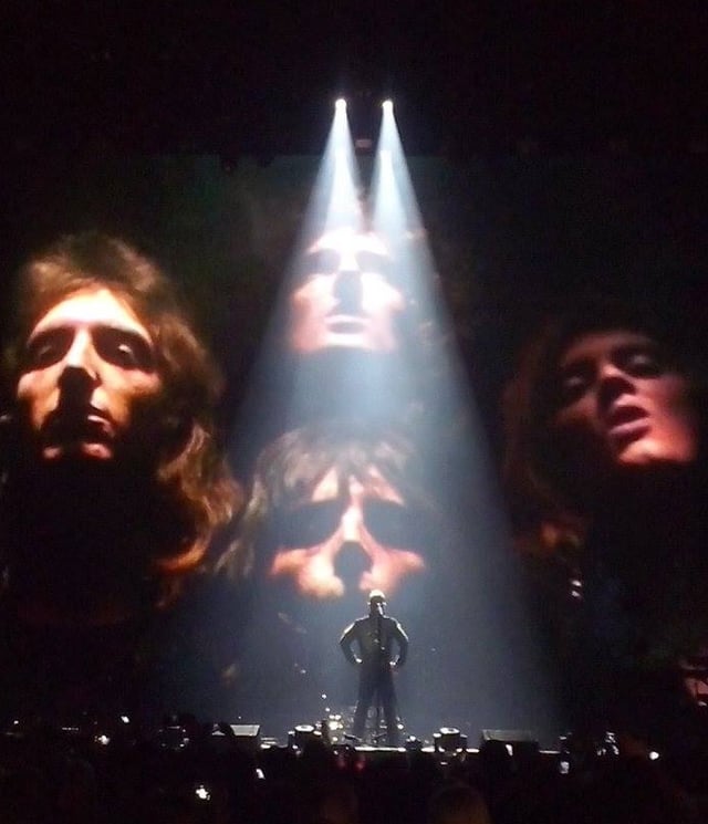 Robbie Williams, on stage in 2015 with the Queen image in the background, performed "We Are the Champions" for the 2001 medieval adventure film A Knight's Tale