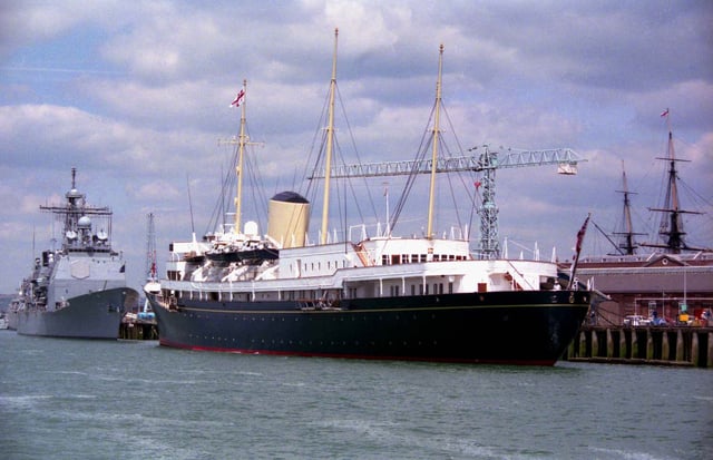 Her Majesty's Yacht Britannia in Portsmouth Harbour during the 50th anniversary of the D-Day Landings in 1994. The masts of HMS Victory can be seen in the background.
