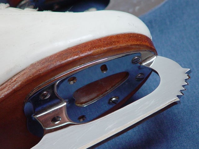 Close-up of a figure skating blade, showing the toe picks, the hollow (groove) on bottom surface of blade, and screw attachment to the boot