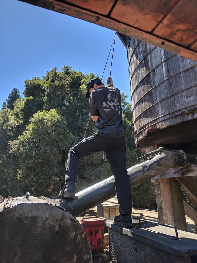A fireman refills the water tank of a steam locomotive.