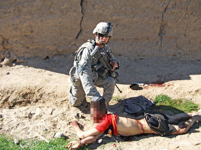 Andrew Holmes poses with the body of Gul Mudin immediately after the boy was killed.