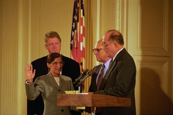 Chief Justice William Rehnquist swears-in Ginsburg as an Associate Justice of the Supreme Court as her husband Martin Ginsburg and President Clinton watch.