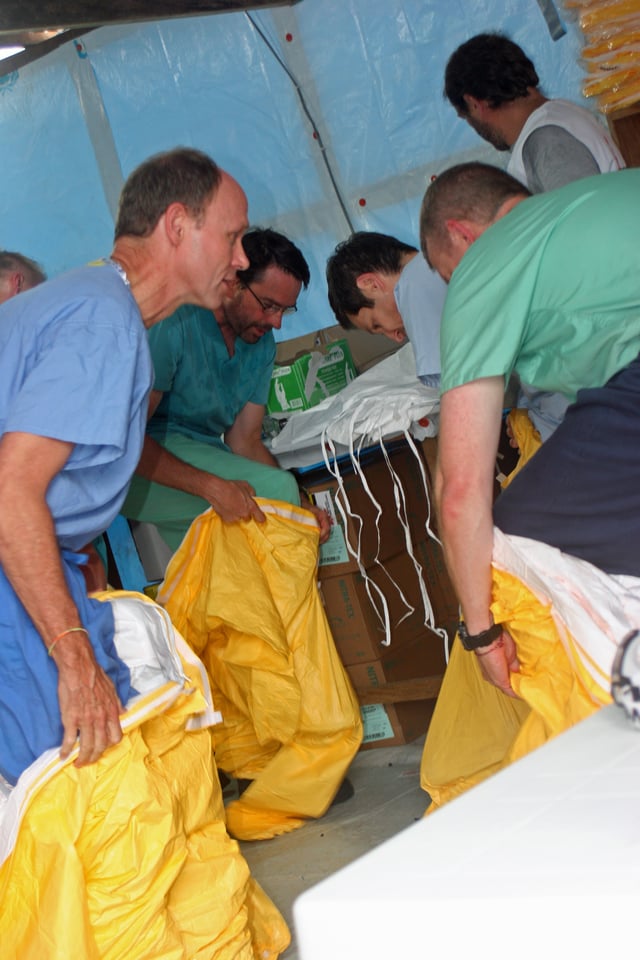 Doctors from MSF and the American CDC put on protective gear before entering an Ebola treatment ward in Liberia, August 2014