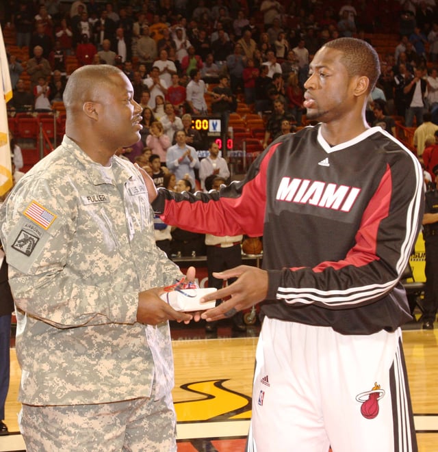 Wade (right) giving a present to a U.S. Army reservist during a March 2, 2009, pregame ceremony