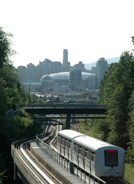 Vancouver's SkyTrain in the Grandview Cut, with downtown Vancouver in the background. The white dome-like structure is the old roof of BC Place Stadium.