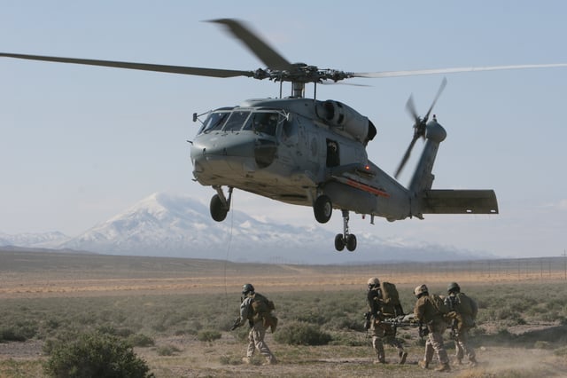 A Seahawk hovers during a simulated casualty evacuation as MARSOC operators carry a stretcher.