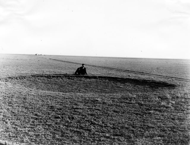 The Great Plains before the native grasses were ploughed under, Haskell County, Kansas, 1897, showing a man sitting behind a buffalo wallow