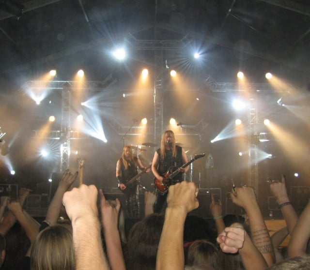Fans raise their fists and make the "devil horns" gesture at a Metsatöll concert.