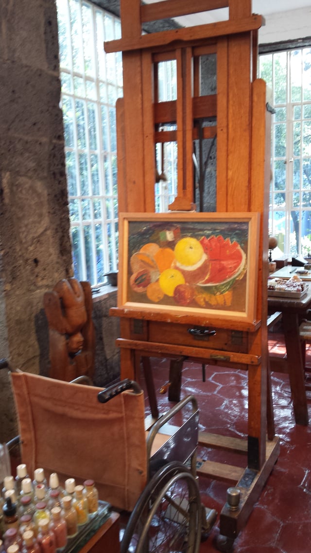 Kahlo's wheelchair and adjustable easel in La Casa Azul, with one of her still lifes from her final years