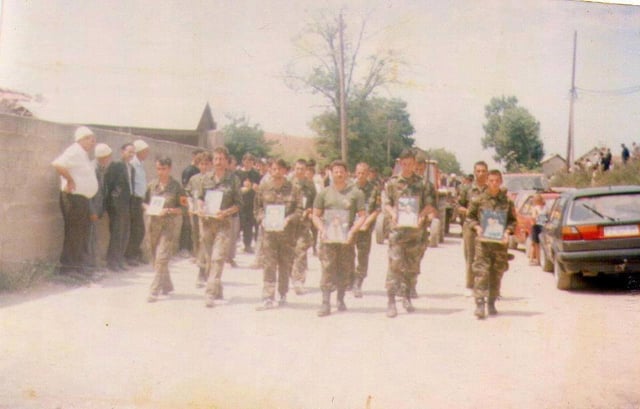 Kosovar Albanian soldiers holding pictures in memory of the men who were killed or went missing in the Velika Kruša massacre