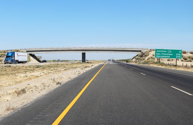 A rural stretch of I-5 in California; two lanes in each direction are separated by a large grassy median and cross-traffic is limited to overpasses and underpasses