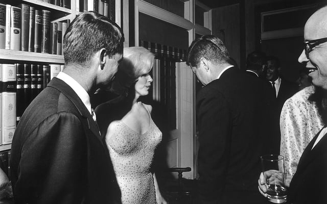 Attorney General Robert F. Kennedy, Marilyn Monroe, and John Kennedy talk during the president's 19 May 1962 early birthday party, where Monroe publicly serenaded JFK with "Happy Birthday, Mr. President"
