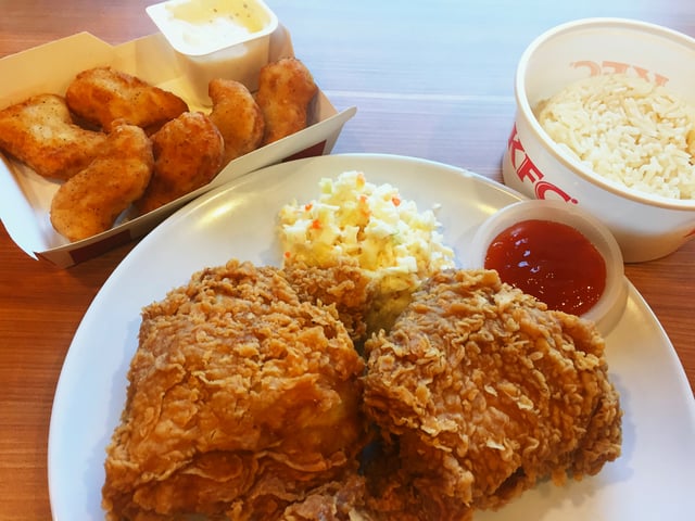 2 pieces of "Hot & Spicy" Chicken combo served with rice, coleslaw and Thai chili sauce; with KFC Chicken nuggets with sour cream sauce on the upper left side of the image. Akin to most Asian markets, the Malaysian KFC similarly offered rice in its menu. Embracing the local culinary tradition, the Malaysian KFC rice draw its inspiration from the local Hainanese chicken rice. Additionally, the KFC chicken nuggets also traced its origin from Malaysia before being expanded to many international outlets.