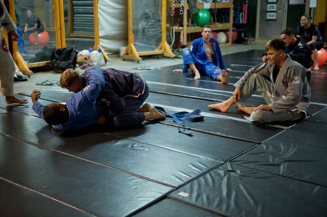 A Brazilian Jiu-Jitsu instructor gently demonstrates how to tackle an opponent.