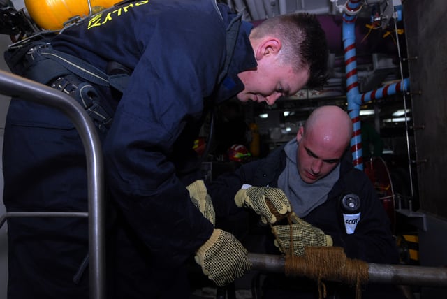 Machinist's Mates gundeck repairing a simulated cracked pipe with soft patch during a general quarters drill aboard USS Ronald Reagan