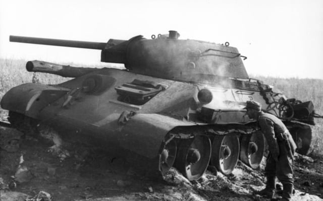 A German soldier inspects a knocked out T-34 during the Battle of Kursk at Pokrovka, 40 kilometres (25 mi) southwest of Prokhorovka.