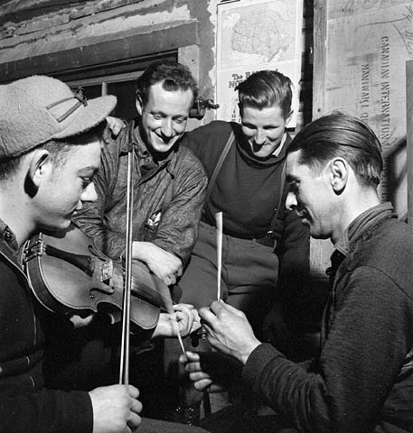 French-Canadian lumberjacks playing the fiddle, with sticks for percussion, in a lumber camp in 1943.