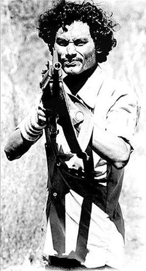 A Farabundo Martí National Liberation Front (FMLN) soldier takes aim during a wartime “road advisory” near Suchitoto, El Salvador (1984).