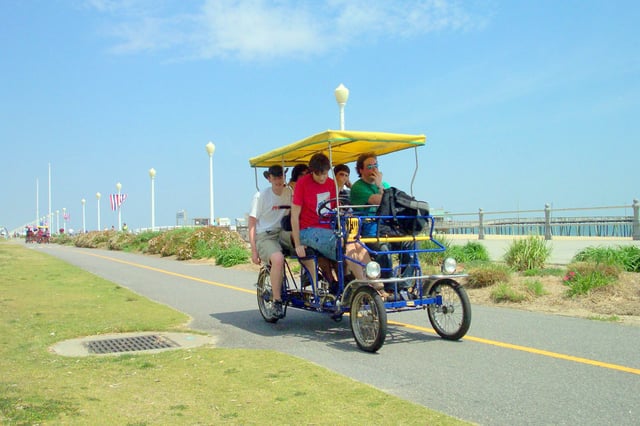 People riding a rental surrey on the boardwalk