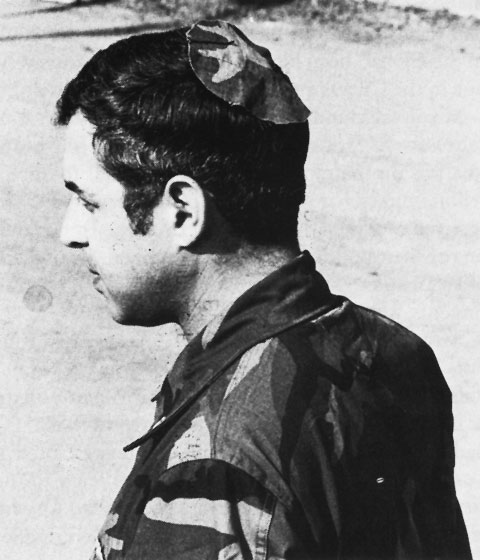Jewish chaplain Rabbi Arnold Resnicoff wears a kippah/yarmulke made from a piece of a Catholic chaplain's camouflage uniform after his own head covering had become bloodied when it was used to wipe the face of a wounded marine during the 1983 Beirut barracks bombing.