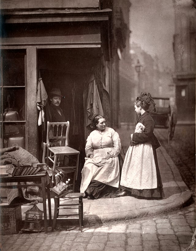 ''The accompanying photograph represents a second-hand clothes shop in a narrow thoroughfare of St. Giles, appropriately called Lumber Court, where several similar tradesmen are grouped together, all dealing in old clothes and furniture of a most varied and dilapidated description. ''