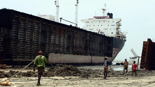 Workers drag steel plate ashore from beached ships in Chittagong, Bangladesh