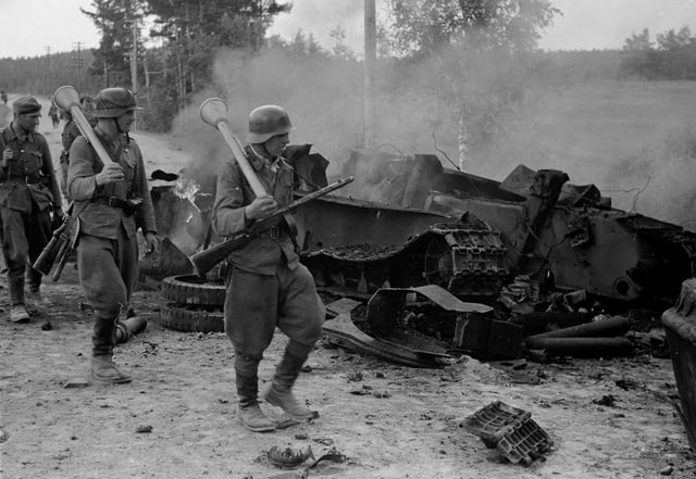 Finnish troops passing by the remains of a destroyed Soviet T-34 at the battle of Tali-Ihantala