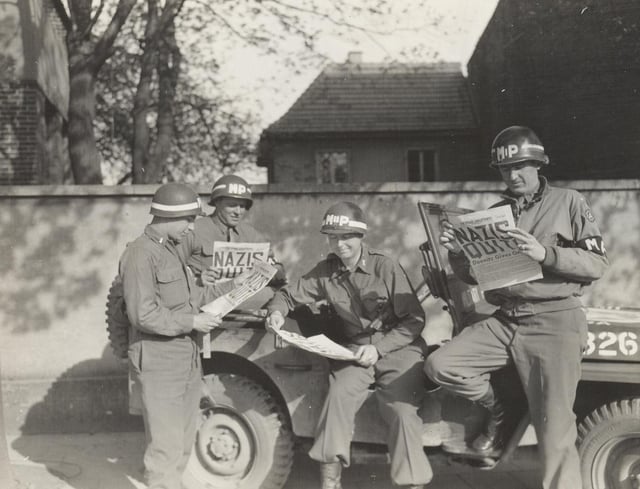 United States military policemen reading about the German surrender in the newspaper Stars and Stripes