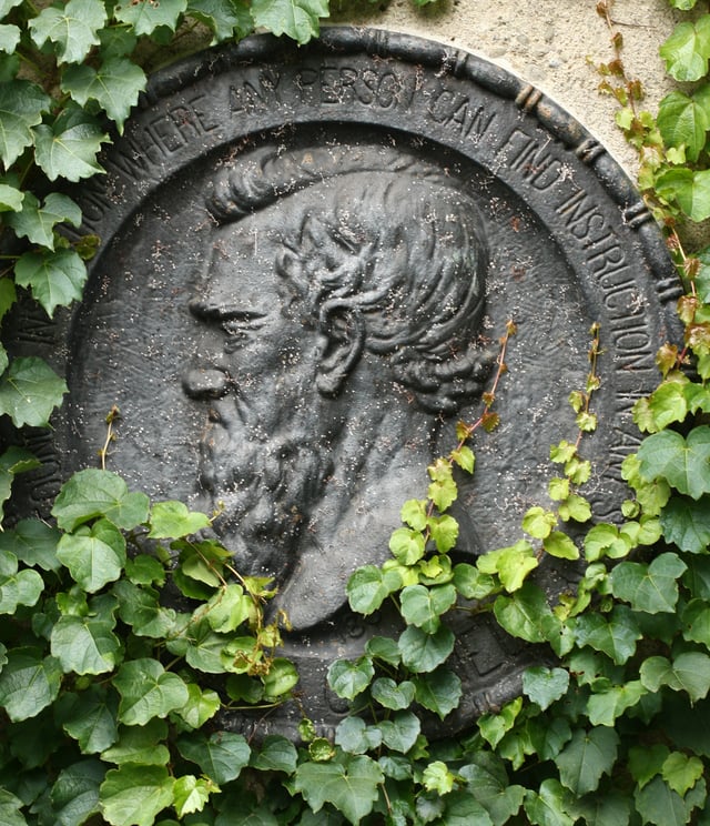 An ivy-covered emblem of Ezra Cornell circumscribed by the university motto