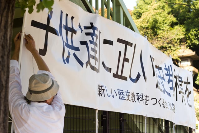 Member of the right-wing revisionist group "Japanese Society for History Textbook Reform" putting up a banner reading "[Give] the children correct history textbooks" in front of the Yasukuni Jinja