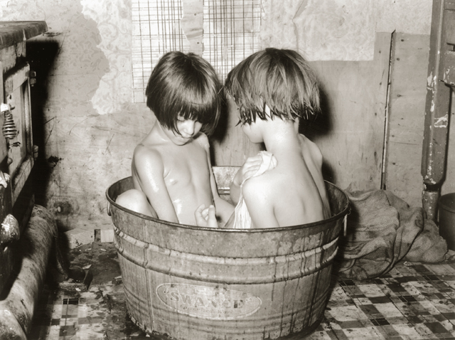 Two children bathing in a small metal bathtub