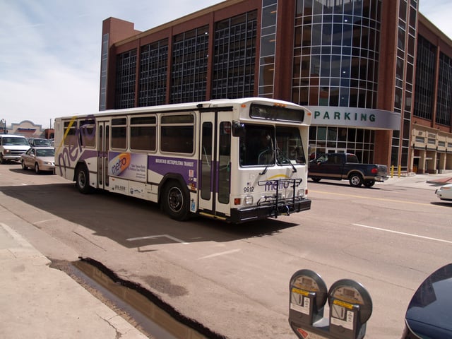 A Metro bus drives past a parking garage in downtown Colorado Springs.