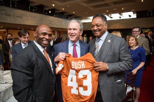 (L–R) Charlie Strong, Texas Longhorns head football coach, George W. Bush and Reverend Jesse Jackson hold up a Texas Longhorns football jersey at the LBJ Presidential Library in 2014