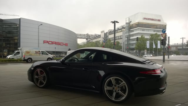 A 911 (991) in front of the factory in which it was assembled, Porschewerk Stuttgart (right), and the manufacturer's central dealership, Porsche Zentrum Stuttgart (left).