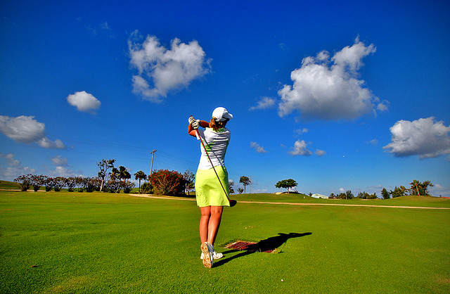A golfer takes an approach shot on the fairway.