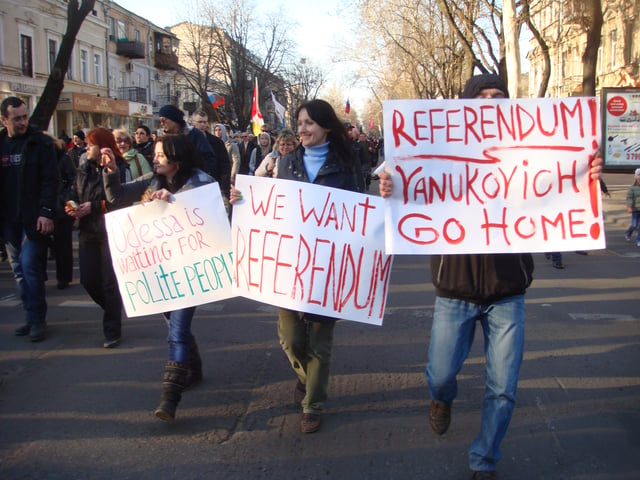 Protesters marching on the streets of Odessa on 30 March 2014; some of them holding banners claiming Yanukovych as Ukraine's legitimate president.