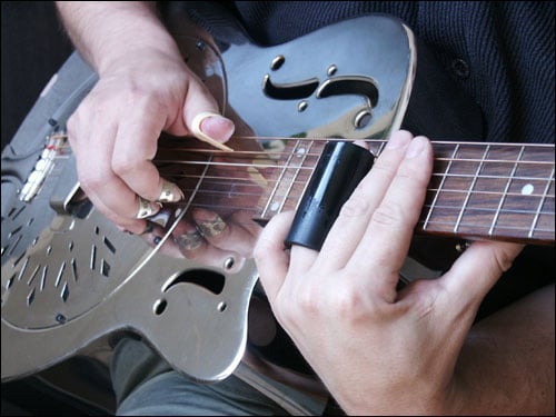 Example of a bottleneck slide, with fingerpicks and a resonator guitar made of metal.