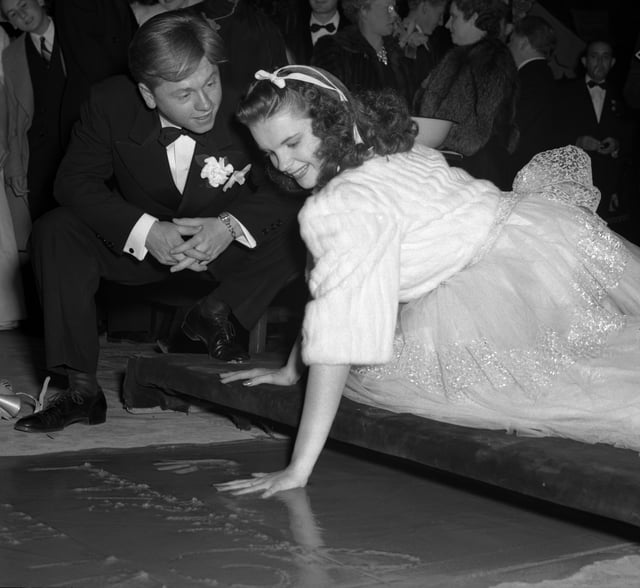 Mickey Rooney watching Garland put her handprint into concrete at Grauman's Chinese Theatre, 1939