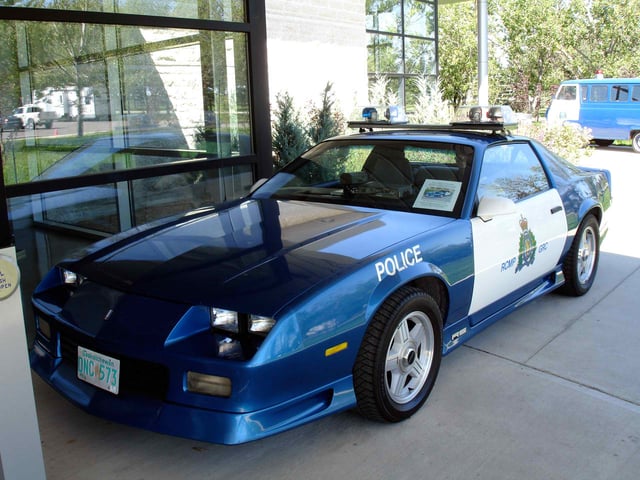 A 1992 Chevrolet Camaro as used by the Royal Canadian Mounted Police in the 1990s, outfitted in a white and blue paint finish with emergency lights on the roof