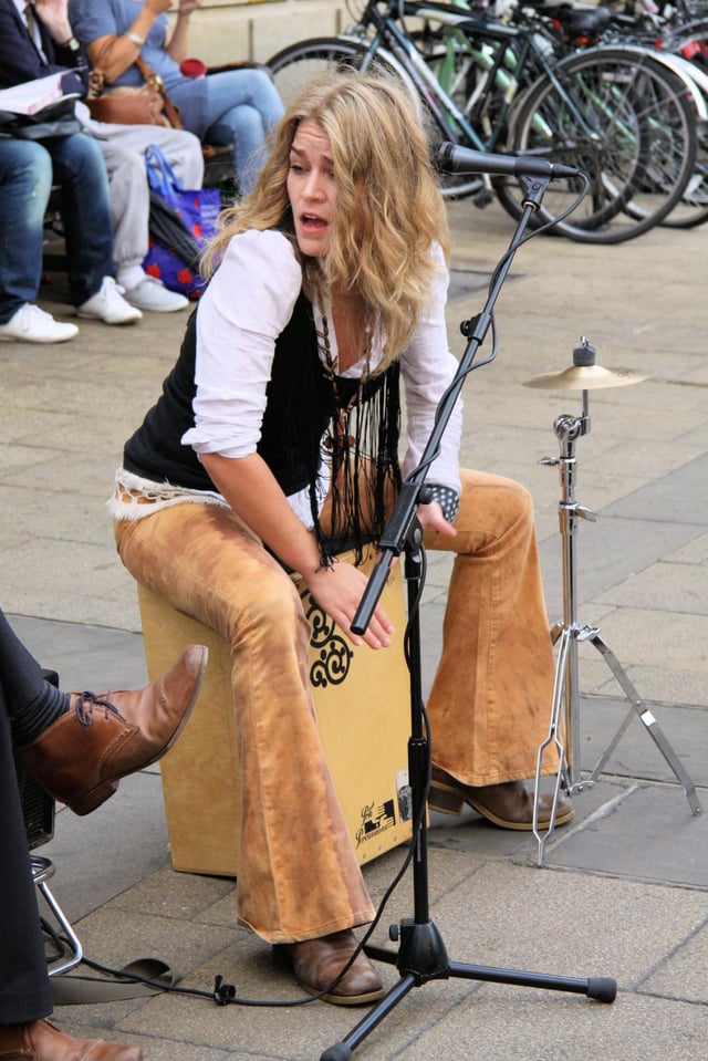 A street musician (Heidi Joubert) playing a decorated cajón