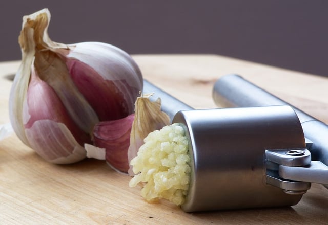 Garlic being crushed using a garlic press
