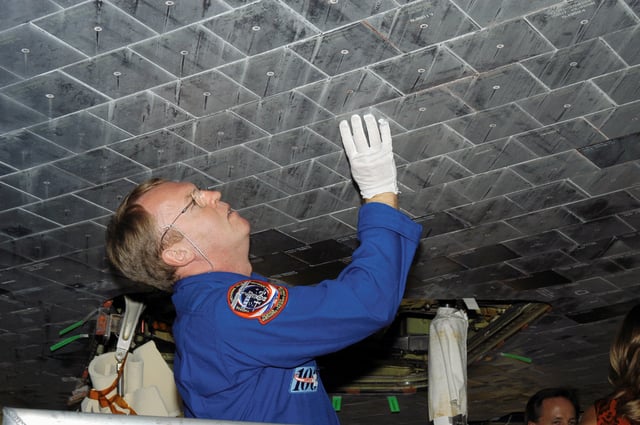 Astronaut Andrew S. W. Thomas takes a close look at TPS tiles underneath Space Shuttle Atlantis.